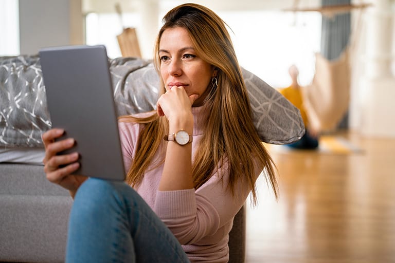 Woman at home reading a blog on her tablet.
